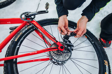 Ein Mittelteil eines Mountainbikers, der sein Fahrrad im Winter im Freien im Schnee befestigt. - HPIF22464