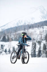 Eine weibliche Mountainbikerin steht auf der Straße im Freien im Winter Natur. kopieren Raum. - HPIF22472