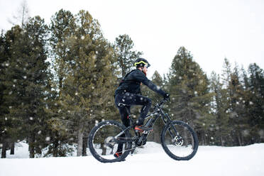 Eine Seitenansicht von Mountainbiker Reiten im Schnee im Freien im Winter Natur. - HPIF22488