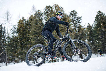 Eine Seitenansicht von Mountainbiker Reiten im Schnee im Freien im Winter Natur. - HPIF22489
