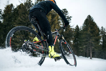 Ein Mittelteil eines Mountainbikers, der im Winter draußen im Schnee fährt. - HPIF22492