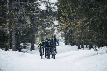 A group of young mountain bikers riding on road outdoors in winter. - HPIF22498