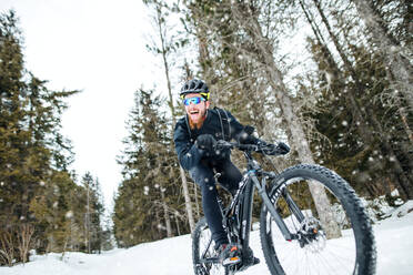 Eine Seitenansicht von Mountainbiker Reiten im Schnee im Freien im Winter Natur. - HPIF22501