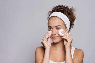 A portrait of a young woman cleaning face in a studio, beauty and skin care. - HPIF22506