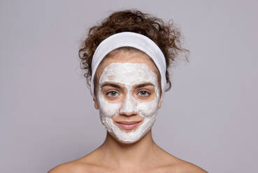 A portrait of a young woman cleaning face with cotton wool in a studio, beauty and skin care. - HPIF22512