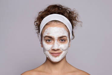 Porträt einer jungen Frau, die in einem Studio ihr Gesicht mit Watte reinigt, Schönheit und Hautpflege. - HPIF22512