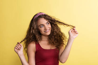 A portrait of a young woman with headband in a studio on a yellow background. - HPIF22534