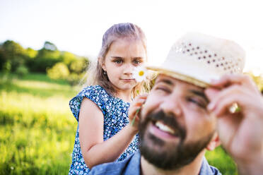 Vater mit kleiner Tochter hat Spaß mit Hut in sonniger Frühlingsnatur. - HPIF22607