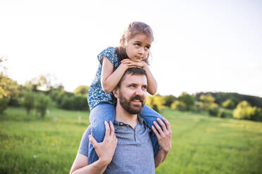 Mature father giving a small daughter a piggyback ride in spring nature. - HPIF22619