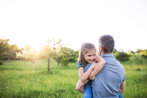 Unbekannter Vater hält eine kleine Tochter in der Natur bei Sonnenuntergang, Raum kopieren. - HPIF22624