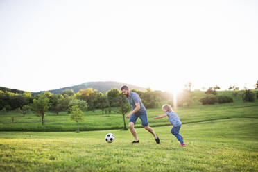 Vater mit einer kleinen Tochter, die mit einem Ball in der sonnigen Frühlingsnatur spielt. - HPIF22638