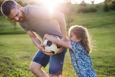 Father with a small daughter playing with a ball in spring nature at sunset. - HPIF22642