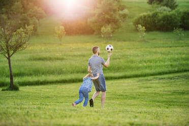 Vater mit einer kleinen Tochter, die mit einem Ball in der sonnigen Frühlingsnatur spielt. - HPIF22643