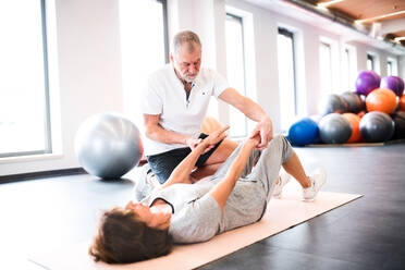 Senior physiotherapist working with an old female patient. - HPIF22650