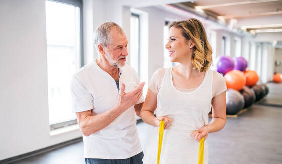 Ein älterer männlicher Physiotherapeut arbeitet mit einer jungen Patientin. - HPIF22666