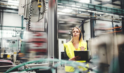 Eine Ingenieurin mit Headset in einer Fabrik bei der Arbeit. Raum kopieren. - HPIF22789