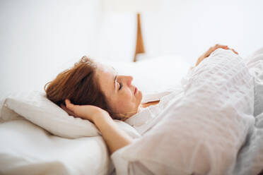 Eine glückliche junge Frau liegt morgens in einem Schlafzimmer im Bett und schläft. - HPIF22810