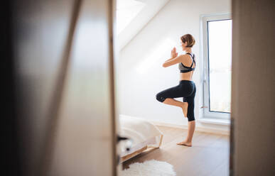 A side view of young woman doing exercise indoors in a bedroom. Copy space. - HPIF22856