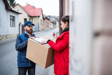 Junge Frau, die ein Paket vom Zusteller an der Tür erhält - Kurierdienstkonzept. - HPIF22962