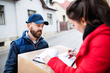 Junge Frau, die ein Paket vom Zusteller an der Tür erhält - Kurierdienstkonzept. - HPIF22963