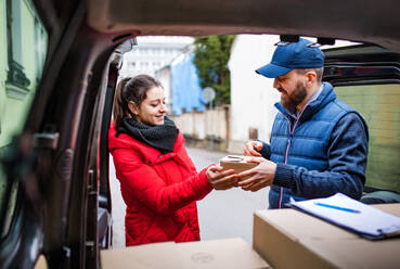 Junge Frau, die ein Paket vom Zusteller erhält - Kurierdienstkonzept. - HPIF22967