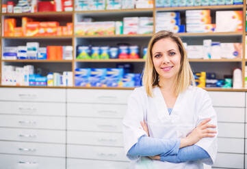 Portrait of a young beautiful friendly female pharmacist, arms crossed. - HPIF22983