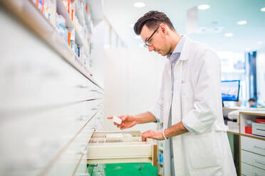 Portrait of a young atrractive friendly male pharmacist, working. - HPIF22994