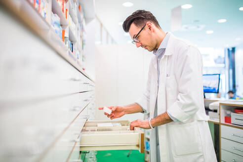 Porträt eines jungen, attraktiven, freundlichen Apothekers bei der Arbeit. - HPIF22994