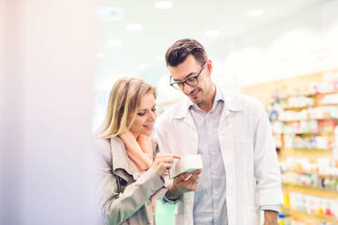 Handsome male friendly pharmacist serving a female customer. - HPIF23000