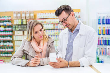 Handsome male friendly pharmacist serving a female customer. - HPIF23002