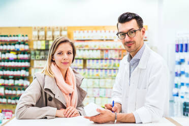 Portrait of handsome male friendly pharmacist with a female customer. - HPIF23003