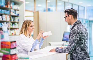 Female friendly pharmacist serving a male customer. - HPIF23004