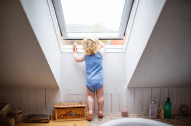 Kleines Kleinkind, das ein Fenster öffnet, häuslicher Unfall, gefährliche Situation zu Hause. - HPIF23049