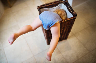 Ein kleiner Junge in einer gefährlichen Situation im Badezimmer. Ein Kleinkind in einem Wäschekorb, die Beine ragen heraus. - HPIF23061
