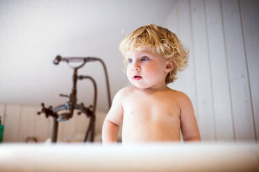 Niedliches Kleinkind, das in der Badewanne im Badezimmer steht. - HPIF23065