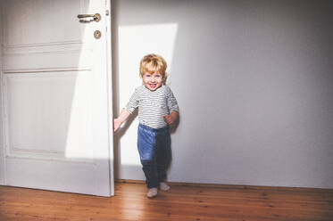 Cute happy toddler boy standing in a bedroom. - HPIF23137