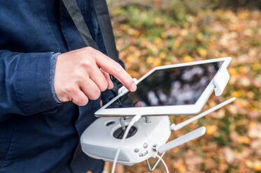 Unrecognizable man with tablet and drone controller standing in autumn park. - HPIF23150