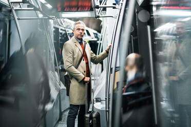 Reifer, gutaussehender Geschäftsmann mit Koffer, der mit der U-Bahn in der Stadt Prag unterwegs ist. - HPIF23163