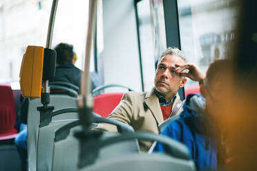 Tired mature handsome businessman travellling by bus in city of Prague. Copy space. - HPIF23184