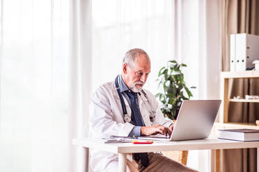 Älterer männlicher Arzt, der am Laptop im Büro arbeitet. - HPIF23193