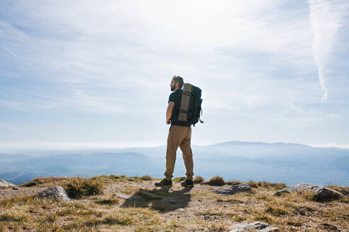 Rückansicht eines reifen Mannes mit Rucksack, der im Sommer in den Bergen wandert und sich ausruht. - HPIF23241