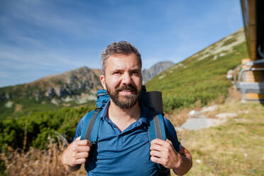 Mature man with backpack hiking in mountains in summer, resting. - HPIF23244