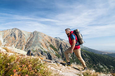 Reifer Mann mit Rucksack, der im Sommer in den Bergen wandert, Kopierraum. - HPIF23252