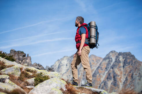 Reifer Mann mit Rucksack, der im Sommer in den Bergen wandert, Kopierraum. - HPIF23256