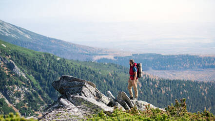 Reifer Mann mit Rucksack, der im Sommer in den Bergen wandert, Kopierraum. - HPIF23259