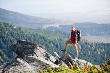 Reifer Mann mit Rucksack beim Wandern in den Bergen im Sommer, beim Ausruhen. - HPIF23260