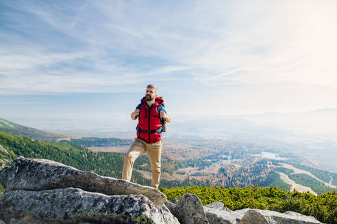 Reifer Mann mit Rucksack beim Wandern in den Bergen im Sommer, beim Ausruhen. - HPIF23266