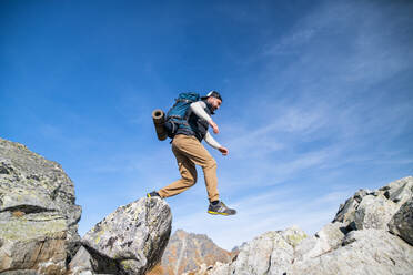 Mature man with backpack hiking in mountains in summer. Copy space. - HPIF23276