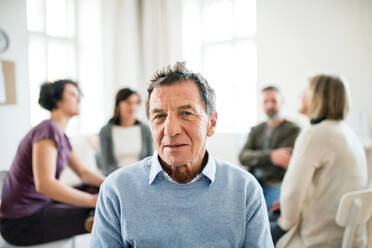 Ein Porträt eines älteren depressiven Mannes während einer Gruppentherapie in Taillenhöhe. - HPIF23320