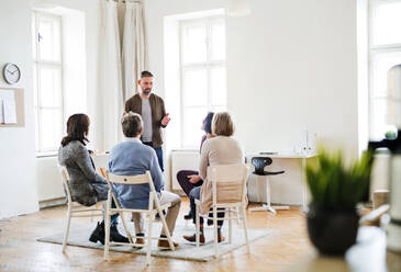 Ein reifer Mann, der während einer Gruppentherapie mit anderen Menschen spricht. - HPIF23323